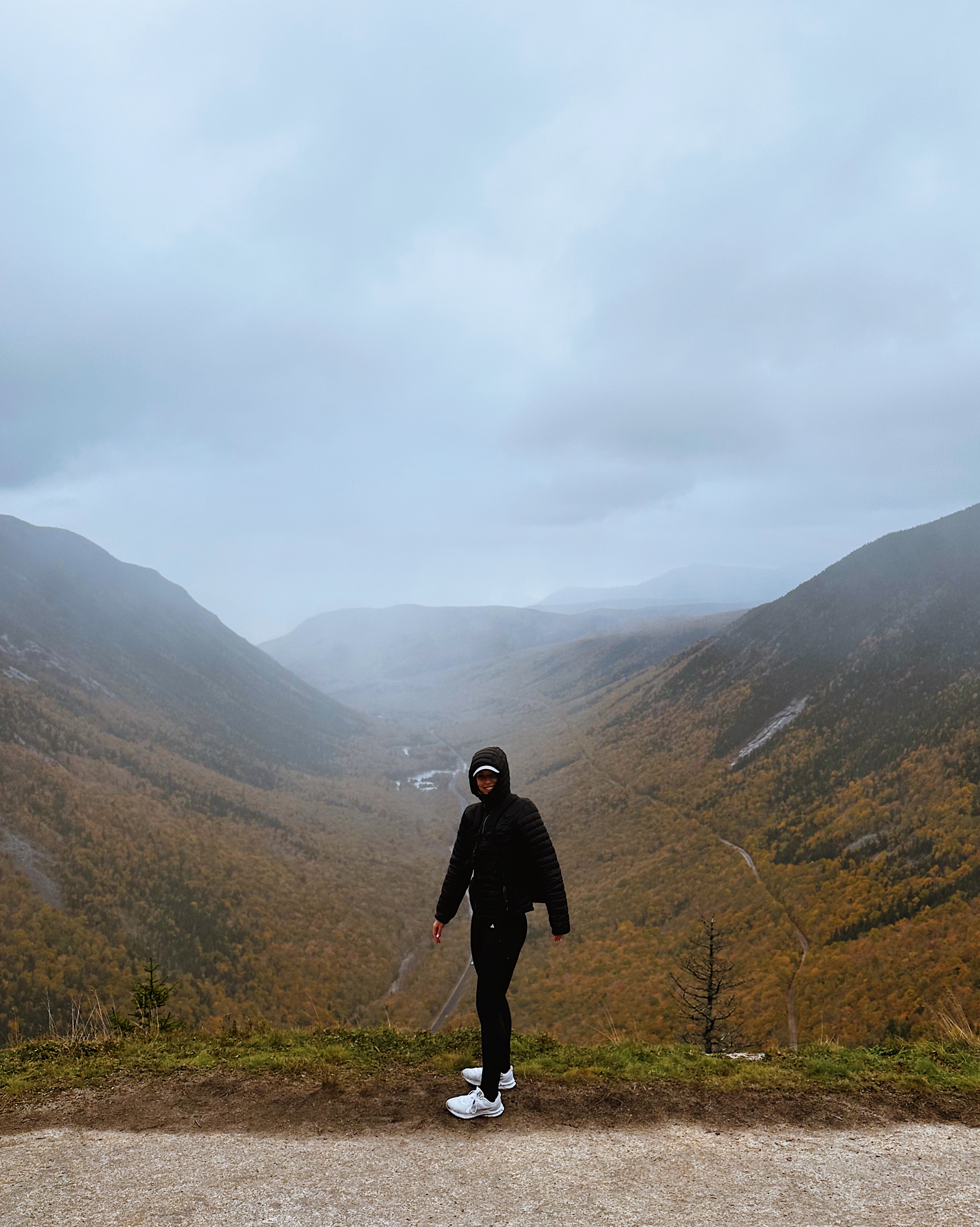 Girl in rain jacket in front of the fall foliage valley.