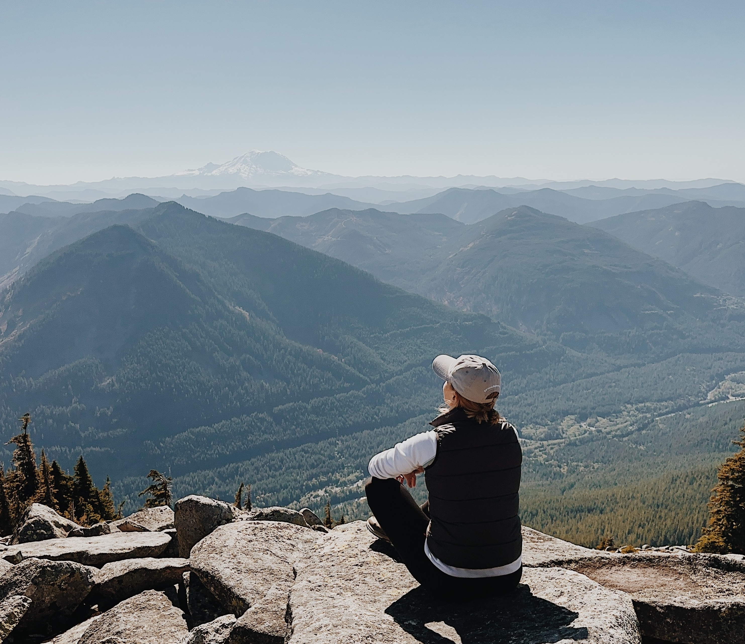 Hiking girl sitting on a rock looking at the mountain valley.